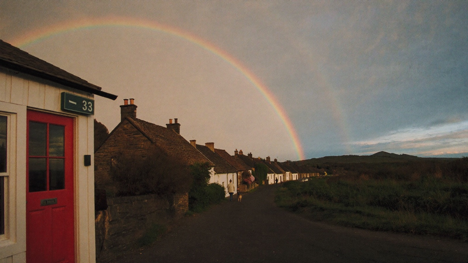 A rainbow over a village lane of stone cottages at dusk