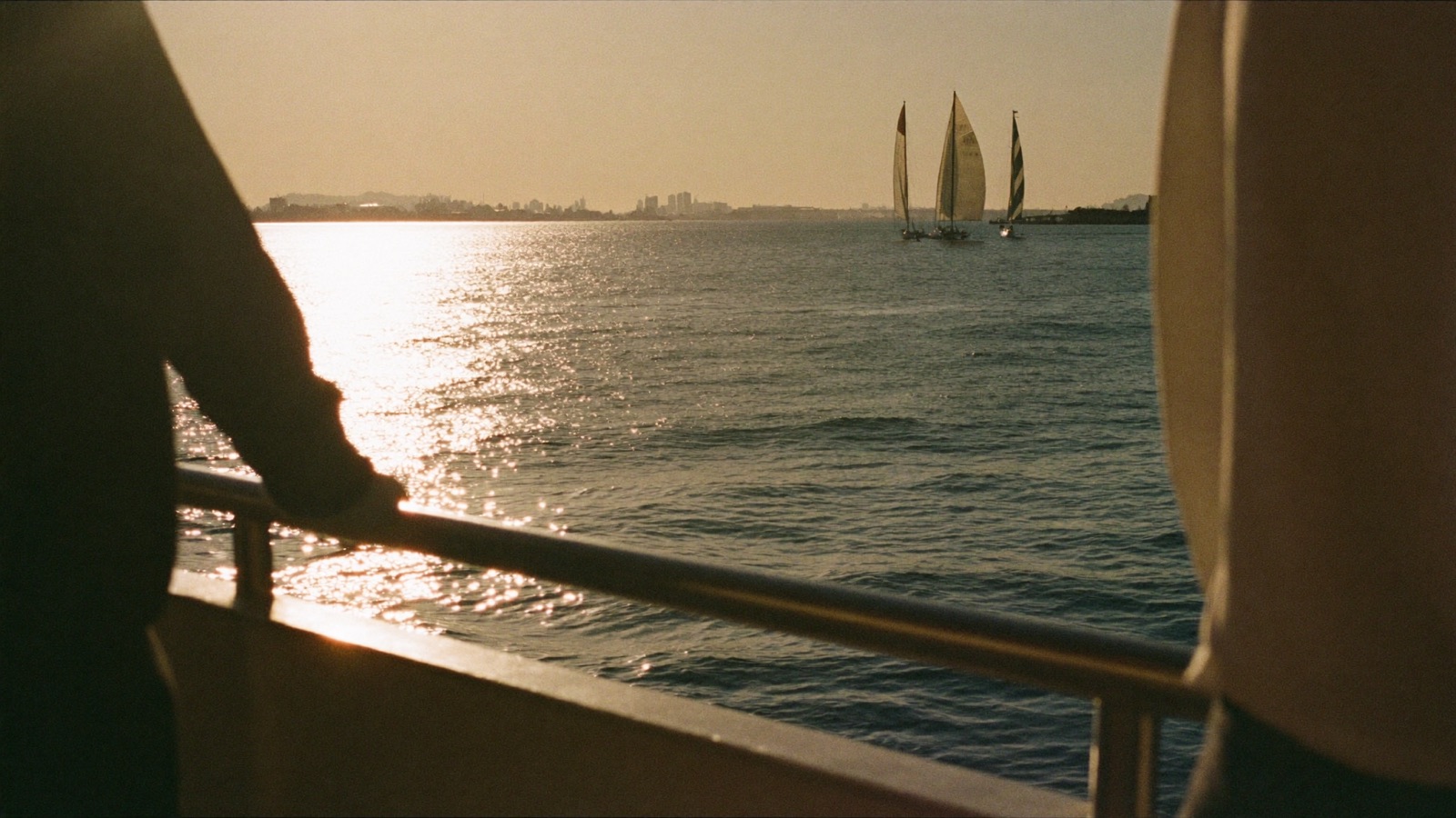 A harbour at golden hour, sailboats out on the water