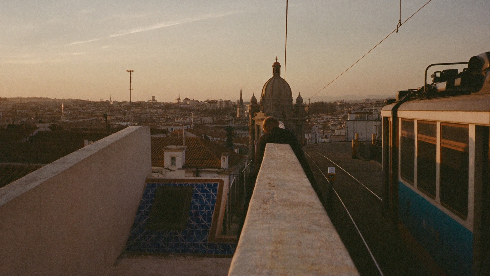 Rooftops and a tram at sunset, seen from a high terrace